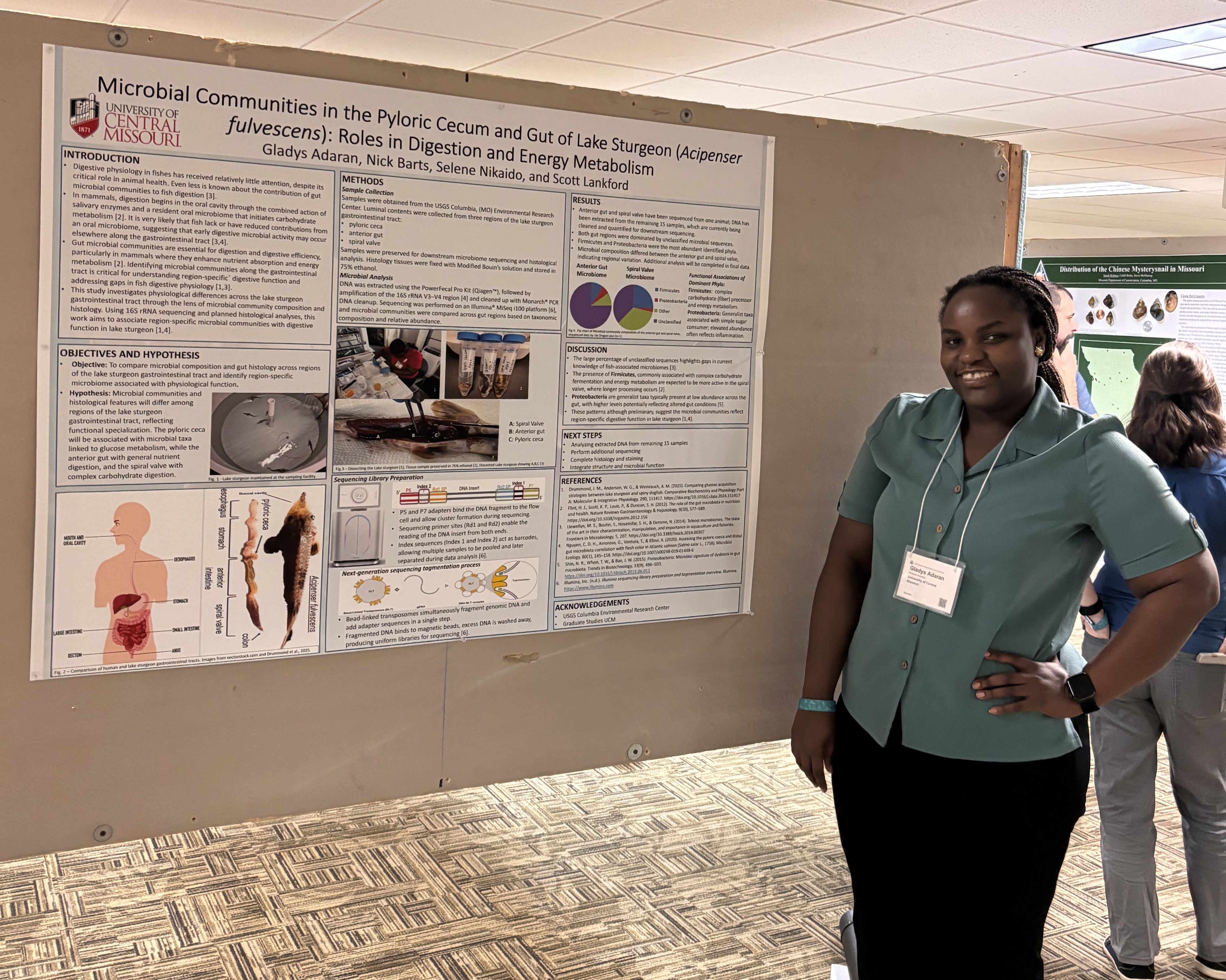 A student stands next to a research poster