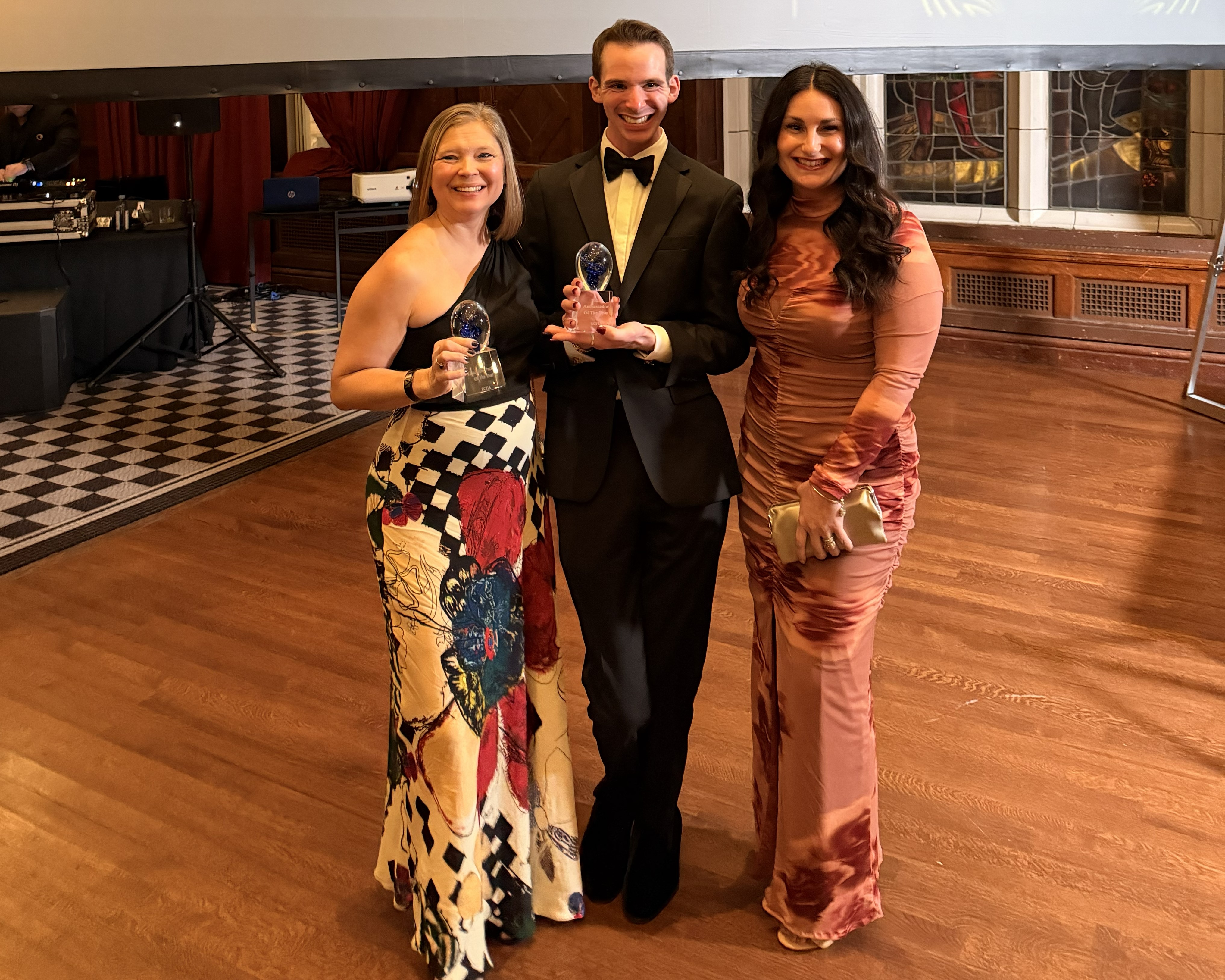 Three people pose for a photo holding awards